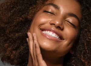 Close-up of a smiling woman with smooth, radiant skin and bright teeth, representing the positive results of a laser peel treatment for skin rejuvenation and improved complexion.