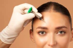 Cosmetologist administering a Botox injection into a woman's forehead, demonstrating a professional anti-wrinkle treatment for smoother skin and facial rejuvenation